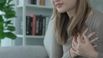 mano hold il petto con cuore attacco sintomi, asiatico donna avere il petto dolore causato di cuore patologia, perdere, dilatazione, allargata coronario cuore, stampa su il il petto con un' doloroso espressione video