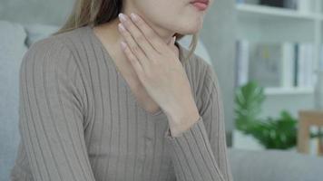 Aisa woman put her hand on her neck due to a sore throat. female tonsillitis causes a inflammation. treated by taking water, taking antibiotics, consult a doctor, virus, corona virus, Influenza, flu video