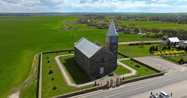 circulaire vlucht en antenne visie Aan gotisch tempel of Katholiek kerk in platteland in de buurt begraafplaats video
