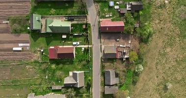 flying over a gravel road in a village with sheds and garden plots video