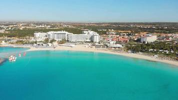 Ayia Napa, Zypern - - 15 .. April, 2023 - - Antenne fliegen Über Luxus Hotel Gebäude mit Pools durch Strand mit Insel Grün Panorama. Weiß Sand Nissi Strand. berühmt Urlaub Ziel video