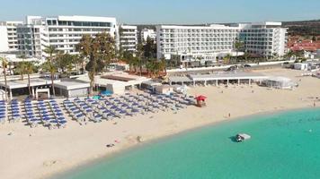 Ayia Napa, Cyprus - 15th april, 2023 - aerial fly over Luxury hotel buildings with pools by beach with island greenery panorama.White sand most famous in Cyprus - Nissi beach video