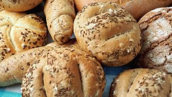 hoop van divers brood broodjes besprenkeld met zout, karwij en sesam. vers rustiek brood van gezuurd deeg. assortiment van vers van bakkerij producten video