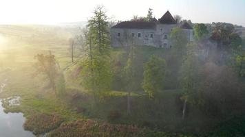 antenn se av svirzh slott nära lviv, ukraina i morgon- dimma på gryning. sjö och omgivande landskap på soluppgång. video