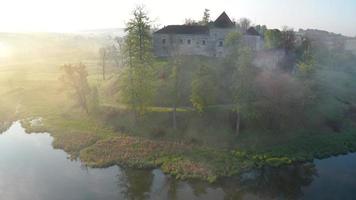 antenn se av svirzh slott nära lviv, ukraina i morgon- dimma på gryning. sjö och omgivande landskap på soluppgång. video