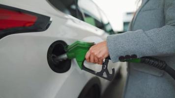 vrouw vult benzine in haar auto Bij een gas- station detailopname video
