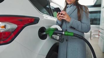 Woman fills petrol into her car at a gas station close-up video