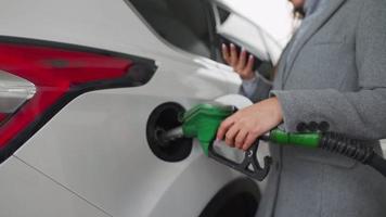 kvinna fyllningar bensin in i henne bil på en gas station närbild video