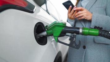 vrouw vult benzine in haar auto Bij een gas- station detailopname video