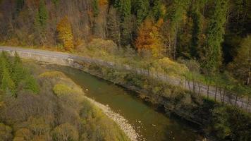 Aerial view of the road and the river near the autumn forest. Scenic autumn landscape video