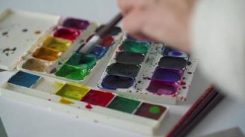 brosse prend différent couleurs de aquarelle des peintures de une palette et mélanges leur fermer video