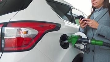 Woman fills petrol into her car at a gas station close-up video