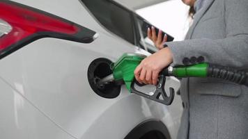 Woman fills petrol into her car at a gas station close-up video