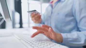 mujer entra crédito tarjeta número en computadora teclado. mujer haciendo en línea compra. en línea pago servicio. cerca arriba de mujer manos sostener crédito tarjeta y utilizando computadora para en línea compras video