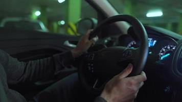 hombre conducción en innovador automatizado coche utilizando auto-estacionamiento piloto automático para estacionamiento en estacionamiento lote. robótico computadora torneado rueda en autodirección modo video