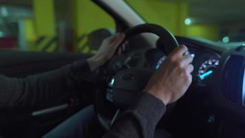 hombre conducción en innovador automatizado coche utilizando auto-estacionamiento piloto automático para estacionamiento en estacionamiento lote. robótico computadora torneado rueda en autodirección modo video