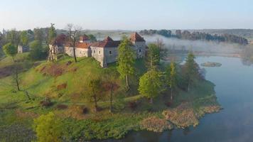 antenn se av svirzh slott nära lviv, ukraina i morgon- dimma på gryning. sjö och omgivande landskap på soluppgång. video