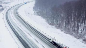 Top view of traffic on a road surrounded by winter forest. Scenic winter landscape video