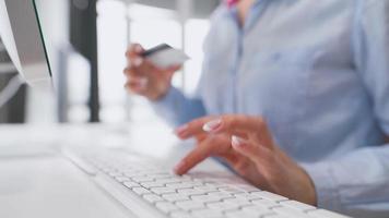 mujer entra crédito tarjeta número en computadora teclado. mujer haciendo en línea compra. en línea pago servicio. cerca arriba de mujer manos sostener crédito tarjeta y utilizando computadora para en línea compras video