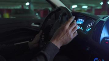 hombre conducción en innovador automatizado coche utilizando auto-estacionamiento piloto automático para estacionamiento en estacionamiento lote. robótico computadora torneado rueda en autodirección modo video