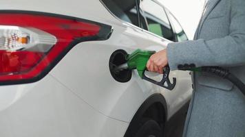 kvinna fyllningar bensin in i henne bil på en gas station närbild video