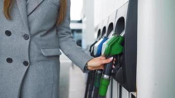 Woman fills petrol into her car at a gas station close-up video