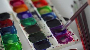 escova leva diferente cores do aguarela tintas a partir de uma paleta e mistura eles fechar-se video