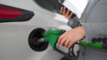 Woman fills petrol into her car at a gas station close-up video