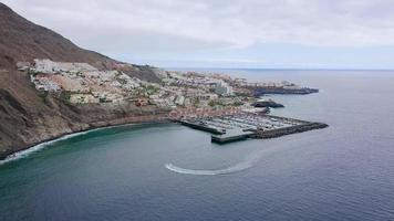 aéreo ver de los gigantes, ver de el centro de deportes acuáticos y el ciudad. salida desde el costa hacia el océano. tenerife, canario islas, España video