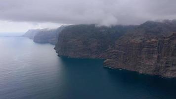 Aerial view of Los Gigantes Cliffs on Tenerife in cloudy weather, Canary Islands, Spain. Accelerated video