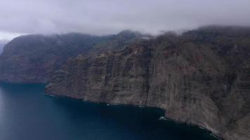 aéreo ver de los gigantes acantilados en tenerife en nublado clima, canario islas, España. acelerado vídeo video