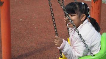 criança tendo Diversão em uma balanço em a Parque infantil dentro público parque video