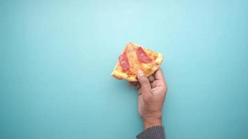 hand holding a slice of cheese pizza on color background video