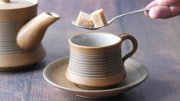 Pouring brown sugar cube in a cup of tea video