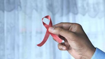 Man holding red HIV ribbon with copy space video