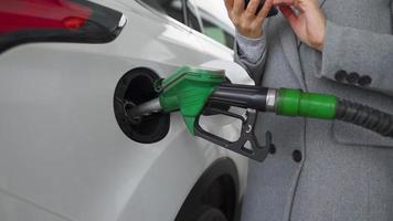 Woman fills petrol into her car at a gas station close-up video