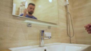 barbado hombre lavados su cara con limpiar agua en el baño. Mañana higiene. lento movimiento video