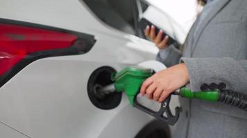 Woman fills petrol into her car at a gas station close-up video