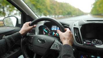 Man driving a car on the road in rainy weather. View from behind the driver. Green trees outside car windows video