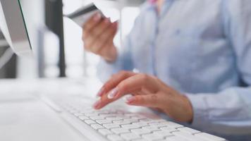 mujer entra crédito tarjeta número en computadora teclado. mujer haciendo en línea compra. en línea pago servicio. cerca arriba de mujer manos sostener crédito tarjeta y utilizando computadora para en línea compras video