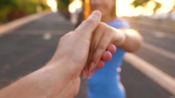 Follow me - happy young woman pulling guy's hand - hand in hand running on a bright sunny day - concept of carefree modern life. Slow motion video