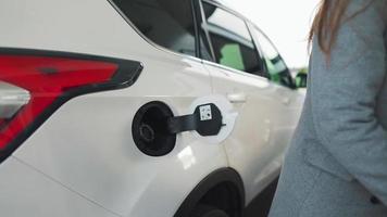 Woman fills petrol into her car at a gas station close-up video