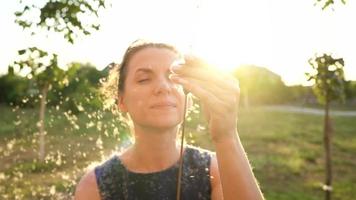 Portrait of pretty woman outdoors in sunny day. Fluff from reeds flies around video