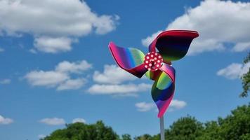 Colorful pinwheel toy on a background of green grass and blue sky video