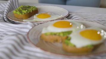 fatiamento torrada com abacate e ovo. líquido gema fluindo. saudável vegano café da manhã. video