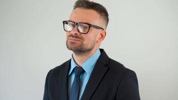 portrait de une officiellement habillé barbu homme avec des lunettes à la recherche à le caméra video