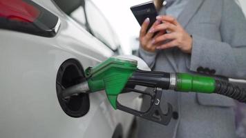 Woman fills petrol into her car at a gas station close-up video