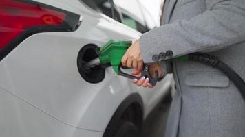 vrouw vult benzine in haar auto Bij een gas- station detailopname video