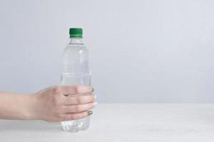 mujer mano con botella de agua en antecedentes foto