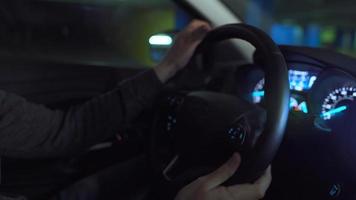 Man driving in innovative automated car using self-parking autopilot for parking on parking lot. Robotic computer turning wheel in autosteering mode video